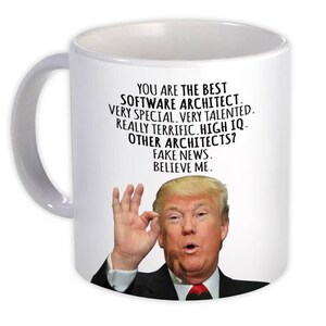 May include: White ceramic mug with a handle. The mug features text that reads "YOU ARE THE BEST SOFTWARE ARCHITECT. VERY SPECIAL, VERY TALENTED. REALLY TERRIFIC. HIGH IQ. OTHER ARCHITECTS? FAKE NEWS. BELIEVE ME." The mug has an image of a man.