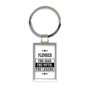 Puede incluir: Un llavero rectangular plateado con el texto "PLUMBER THE MAN. THE MYTH. THE LEGEND." en negro, con tres estrellas arriba y abajo del texto. El llavero tiene un anillo plateado para sujetar llaves.