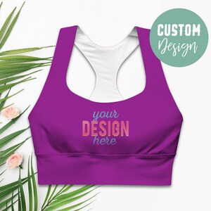 May include: Purple sports bra with a white racerback and the text "your DESIGN here" in a colorful gradient.