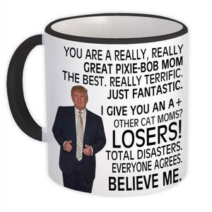 Puede incluir: Taza de cerámica blanca con borde y asa negros. La taza presenta una imagen en blanco y negro de un hombre con traje y una cita que dice: "Eres una mamá pixie-bob realmente, realmente genial. La mejor. Realmente fantástica. Simplemente fantástica. Te doy una A+ otras mamás de gatos? ¡Perdedores! Desastres totales. Todos están de acuerdo. Créeme."