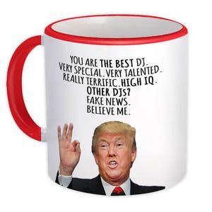 May include: White ceramic mug with a red interior and handle. The mug features a portrait of a man and text that reads "YOU ARE THE BEST DJ. VERY SPECIAL. VERY TALENTED. REALLY TERRIFIC. HIGH IQ. OTHER DJS? FAKE NEWS. BELIEVE ME."