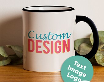 May include: White ceramic mug with a black rim and handle. The mug has the text "Custom DESIGN" in colorful letters. A green circle sticker with the text "Text Image Logo" is on the table next to the mug.