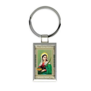 May include: Silver keyring with a rectangular image of a woman holding a plate and a branch. The image is surrounded by a decorative border.