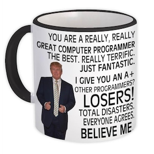 Pode incluir: Caneca de cerâmica branca com alça e borda pretas. A caneca apresenta uma foto de um homem de terno e a frase: "VOCÊ É UM PROGRAMADOR DE COMPUTADOR REALMENTE, REALMENTE ÓTIMO...PERDEDORES! ACREDITE EM MIM."