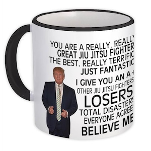 May include: White ceramic mug with a black handle and rim. The mug features a photo of a man in a suit and tie, along with text that reads "YOU ARE A REALLY, REALLY GREAT JIU JITSU FIGHTER THE BEST...BELIEVE ME."