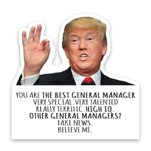 May include: A white sticker featuring a portrait of a man in a black suit and red tie, giving an "okay" hand gesture. Text on the sticker reads: "YOU ARE THE BEST GENERAL MANAGER...FAKE NEWS. BELIEVE ME."
