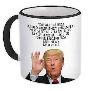 Puede incluir: Taza de cerámica blanca con asa y borde negros. La taza presenta el texto "YOU ARE THE BEST RADIO FREQUENCY ENGINEER. VERY SPECIAL. VERY TALENTED. REALLY TERRIFIC. HIGH IQ. OTHER ENGINEERS? FAKE NEWS. BELIEVE ME."
