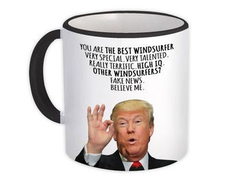 May include: White ceramic mug with a black handle and rim. The mug features a portrait of a man and text that reads "YOU ARE THE BEST WINDSURFER...FAKE NEWS. BELIEVE ME."
