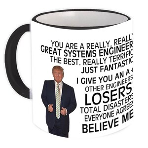 May include: White ceramic mug with a black handle and rim. The mug features a photo of a man in a suit and text that reads "YOU ARE A REALLY, REALLY GREAT SYSTEMS ENGINEER THE BEST...LOSERS...BELIEVE ME."