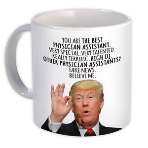 May include: White ceramic mug with a curved handle. The mug features text that reads "YOU ARE THE BEST PHYSICIAN ASSISTANT. VERY SPECIAL, VERY TALENTED. REALLY TERRIFIC. HIGH IQ. OTHER PHYSICIAN ASSISTANTS? FAKE NEWS. BELIEVE ME." and an image of a man.