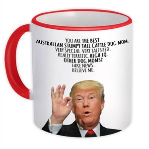 May include: White ceramic coffee mug with a red rim. The mug features a picture of Donald Trump and text that reads "You are the best Australian Stumpy Tail Cattle Dog Mom. Very special, very talented. Really terrific. High IQ. Other dog moms? Fake news. Believe me."