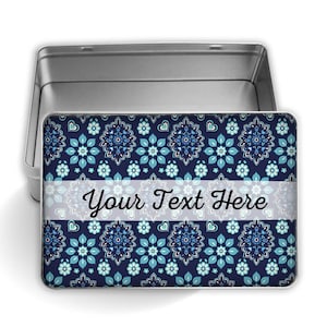 Puede incluir: Una caja metálica rectangular abierta, con un estampado floral azul marino y detalles en azul claro. El diseño incluye el texto "Your Text Here" en una banda blanca. El interior de la caja es plateado. El patrón floral es simétrico.