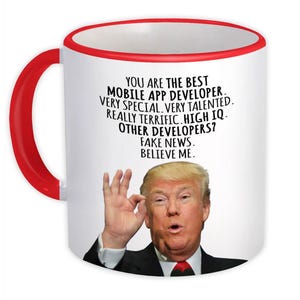 Può includere: Tazza in ceramica bianca con manico e bordo rossi. La tazza presenta un ritratto di un uomo e il testo "YOU ARE THE BEST MOBILE APP DEVELOPER. VERY SPECIAL. VERY TALENTED. REALLY TERRIFIC. HIGH IQ. OTHER DEVELOPERS? FAKE NEWS. BELIEVE ME."