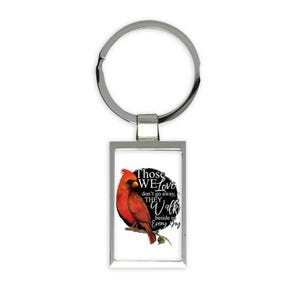 Puede incluir: Un llavero plateado con un dije rectangular que presenta un pájaro cardenal rojo y el texto "Those we love don't go away, they walk beside us every day."