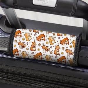 May include: Luggage handle wrap with a repeating pattern of cartoon hamsters in various poses, including some with wings and bow ties, on a white background. The wrap is designed to fit over a suitcase handle.