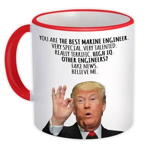 Può includere: Tazza in ceramica bianca con manico e bordo rossi. La tazza presenta il testo "YOU ARE THE BEST MARINE ENGINEER. VERY SPECIAL, VERY TALENTED. REALLY TERRIFIC. HIGH IQ. OTHER ENGINEERS? FAKE NEWS. BELIEVE ME." e l'immagine di un uomo.