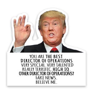 May include: A white sticker with an image of a man in a black suit and red tie, giving an "okay" hand gesture. The sticker has text that reads "YOU ARE THE BEST DIRECTOR OF OPERATIONS...FAKE NEWS. BELIEVE ME."