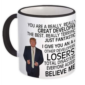 Könnte beinhalten: Weißer Keramikbecher mit schwarzem Henkel und Rand. Der Becher zeigt ein Foto eines Mannes in Anzug und Krawatte mit dem Text "YOU ARE A REALLY, REALLY GREAT DEVELOPER...BELIEVE ME."