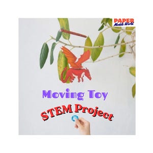 May include: A red paper dragon model with orange wings suspended from a branch. The text Paper Models World, Moving Toy, and STEM Project appear in the image. A hand holds a small blue circular object below the dragon, which is a paper craft.