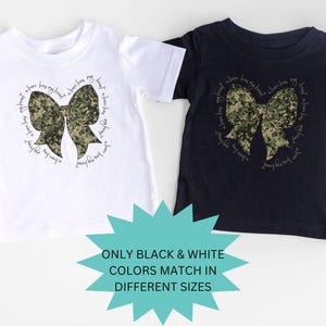 Peut inclure: Deux t-shirts avec un n&oelig;ud camouflage et le texte "J'ai un h&eacute;ros dans mon c&oelig;ur, un h&eacute;ros dans ma famille, un h&eacute;ros qui m'aime" sur chaque t-shirt. Les t-shirts sont disponibles en noir et blanc.