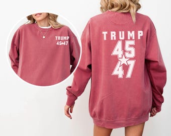 May include: A maroon-colored sweatshirt with long sleeves. The front of the sweatshirt has the text "TRUMP 45*47" in white. The back of the sweatshirt has the word "TRUMP" above the numbers "45" and "47" with a star in between.