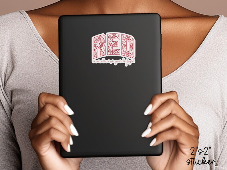 May include: A black tablet with a red sticker that says "RED" in a decorative font. The sticker also has the text "remember everyone deployed" in a script font. The sticker is 2" x 2".
