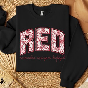 May include: Black sweatshirt with the word "RED" in a floral design. The text "remember everyone deployed" is below the word "RED". The sweatshirt is a crew neck style.