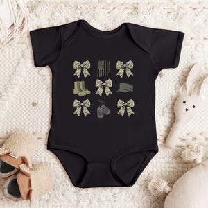 May include: Black bodysuit with a camouflage print featuring bows, dog tags, boots, and a hat.