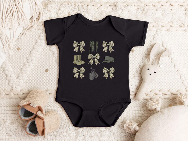 May include: Black bodysuit with a camouflage print featuring bows, dog tags, boots, and a hat.