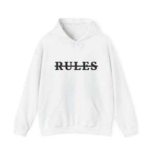Peut inclure: Sweat à capuche blanc avec une poche avant et un cordon de serrage. Le mot "RULES" est imprimé sur la poitrine avec un effet 3D noir, rouge et vert.