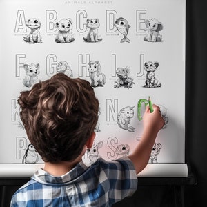 May include: A black and white poster with an alphabet of animals. The poster is on a black easel and a child is pointing to the letter N with a green marker.