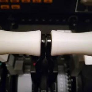 May include: Close-up of a pair of white throttle handles with black accents. The handles are attached to a black metal base.