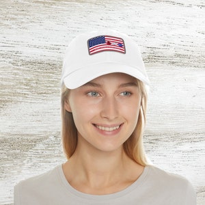 Könnte beinhalten: Weiße Baseballkappe mit einem roten, weißen und blauen amerikanischen Flaggen-Patch, auf dem "United States of America" steht.