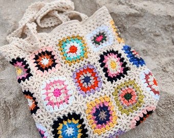 May include: A colorful crocheted tote bag with a square pattern. The bag is made of beige yarn with multi-colored squares featuring a variety of colors, including pink, blue, green, yellow, and red.