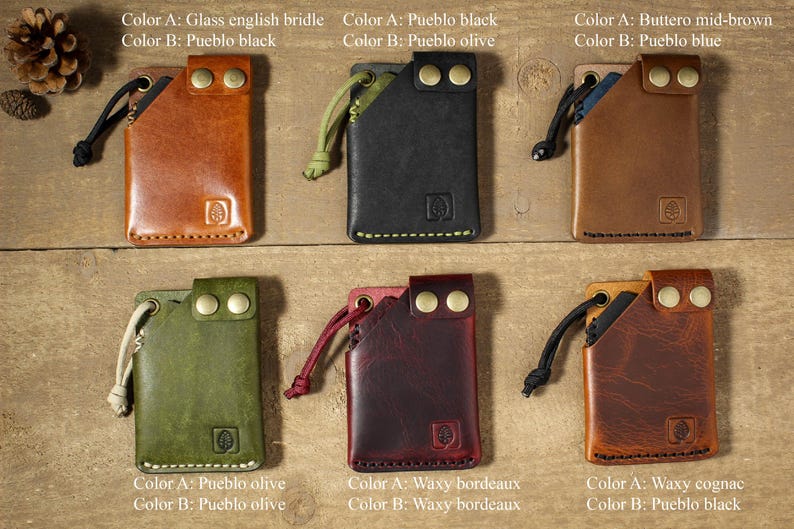 May include: Six leather card holders with different color combinations. Each holder has a small loop on the top and two brass rivets on the front. The holders are arranged in two rows of three.