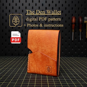 以下が含まれることがあります： 幾何学模様とステッチエッジが特徴の、手作りのオレンジ色の革製ウォレット。 ウォレットには、エンボス加工されたロゴと、「The Den Wallet」のテキスト、説明書、PDFパターンが付属しています。