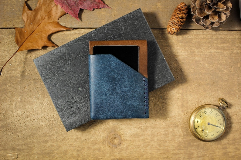 May include: A blue leather wallet with a brown leather trim and a stitched edge. The wallet is closed and sitting on a wooden surface.