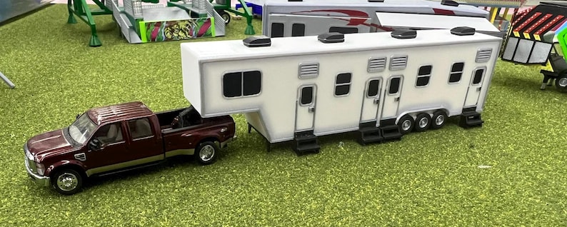 May include: A burgundy pickup truck towing a white fifth wheel camper. The camper has multiple windows and a door on each side.