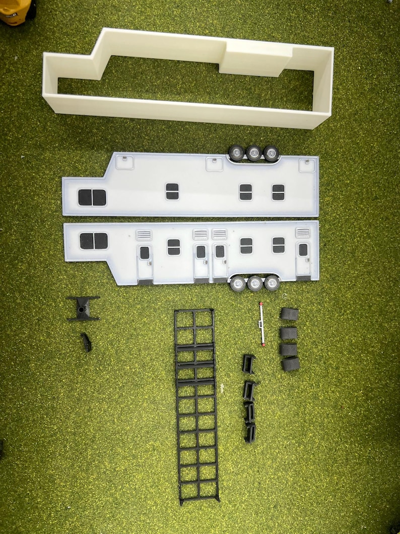 May include: A white model kit of a large semi-trailer truck with a flatbed trailer. The kit includes the cab, the trailer, and a ladder. The kit is made of plastic and is unassembled.