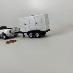 May include: A white toy pickup truck towing a white trailer with two axles. The trailer has two doors and a vent on the side. A penny is in the foreground.