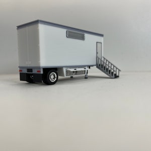 May include: White trailer with a gray door and a set of stairs leading up to the door. The trailer has a small vent on the side.
