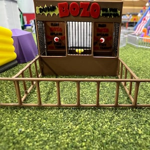 May include: A brown wooden carnival game booth with a red sign that says "Dunk Bozo". The booth has two windows with red and white signs that say "Bank Bozo Splash".