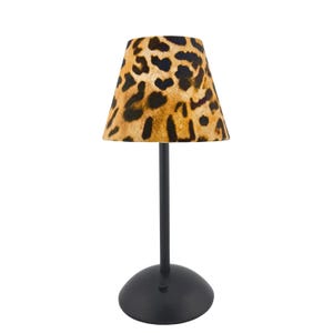 Puede incluir: Una pequeña lámpara de mesa negra con una pantalla con estampado de leopardo. La pantalla tiene forma de cono cónico con un fondo marrón y manchas marrones oscuras. La lámpara tiene un tallo negro delgado y una base redonda negra.