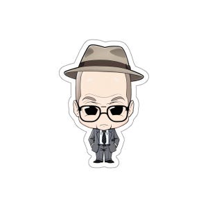 May include: A sticker featuring a cartoon illustration of a man in a gray suit, black glasses, and a fedora hat. The character has a serious expression and is standing with his hands in his pockets. The sticker is die-cut with a white border.