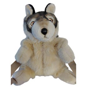 May include: A plush wolf backpack with a cream-colored body, gray and black head, and tan straps. The wolf has a black nose, brown eyes, and upright ears. The backpack is designed to look like a friendly wolf.