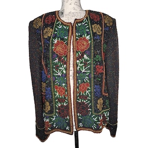 May include: A black beaded jacket with a floral design. The jacket has a long sleeve and a front closure. The beads are in various colors, including red, green, blue, and gold.