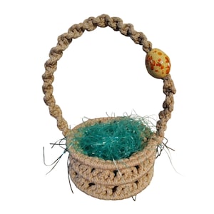 May include: A small, beige crocheted basket with a woven handle and a decorative egg-shaped bead. The basket is filled with bright green shredded paper. The egg bead is yellow with orange speckles. The basket is likely for Easter.