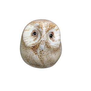 May include: A white ceramic owl figurine with brown speckles and black eyes. The owl has a round head and a small beak.