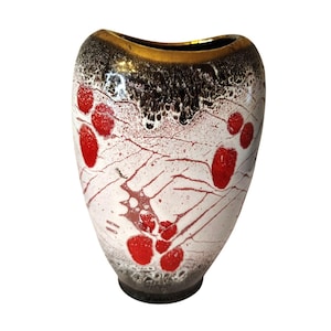 May include: A decorative ceramic vase with a unique design. The vase features a white base with red splotches and a network of red lines. The top rim is gold, with a dark brown and black textured band. The vase has a rounded shape.