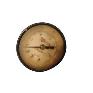 Könnte beinhalten: Ein Vintage-Druckmessgerät der Watts Regulator Co. mit einem schwarzen Metallgehäuse und einem cremefarbenen Zifferblatt. Das Messgerät zeigt Zahlen und Markierungen in Schwarz und Rot an, mit einer Nadel, die auf Null zeigt. Das Messgerät zeigt kg/cm2 an.